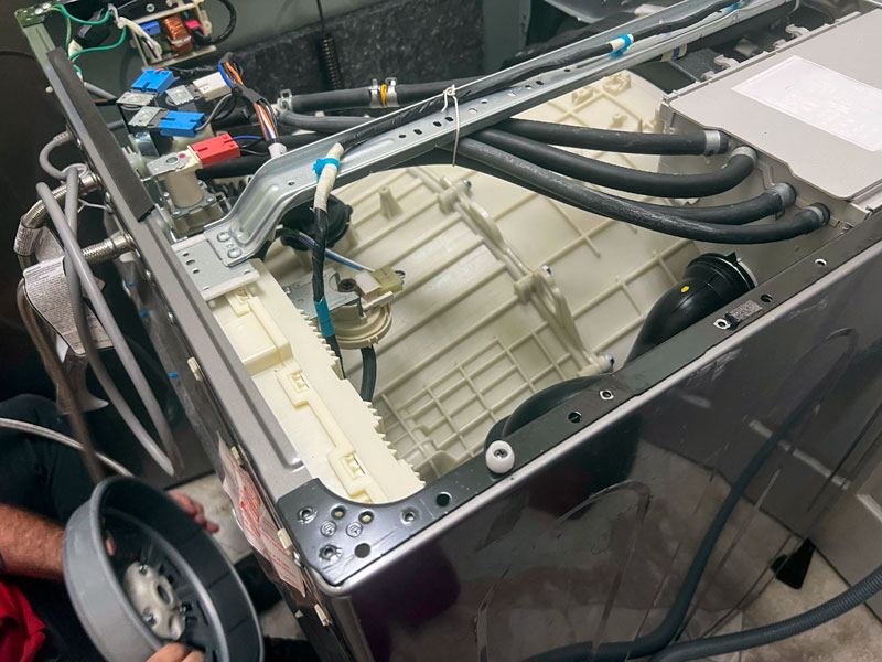 Washing-Machine-Repair appliance repair person is fixing a clothes washing machine in a home.